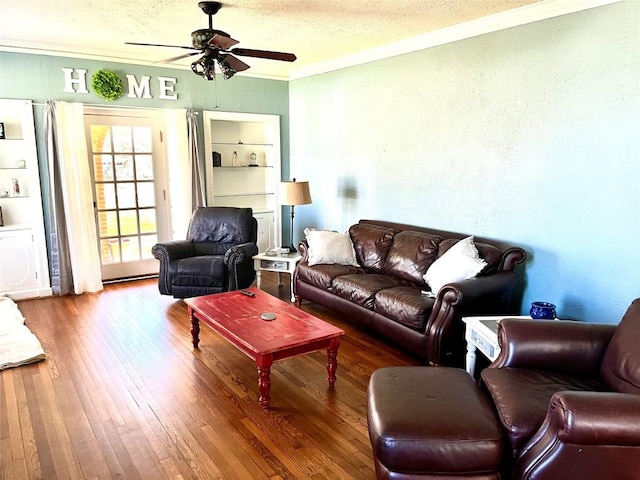 living room featuring ceiling fan, wood-type flooring, a textured ceiling, and ornamental molding