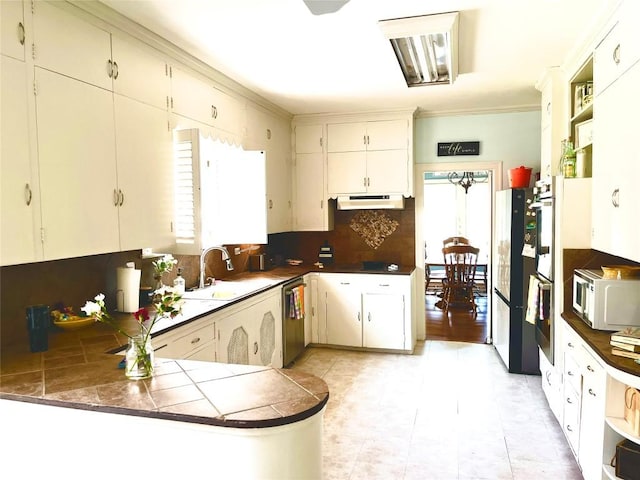 kitchen featuring kitchen peninsula, tasteful backsplash, stainless steel dishwasher, sink, and tile countertops