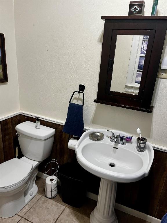 bathroom with tile patterned flooring, toilet, and wood walls