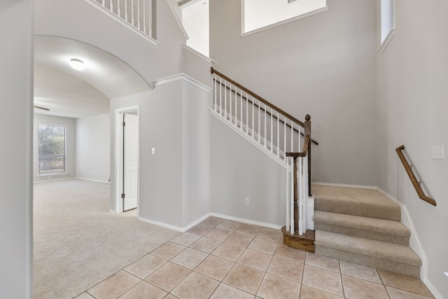 30004 Oakland Hills Dr, Georgetown, TX 78628 - staircase with arched walkways, tile patterned flooring, a high ceiling, and carpet flooring