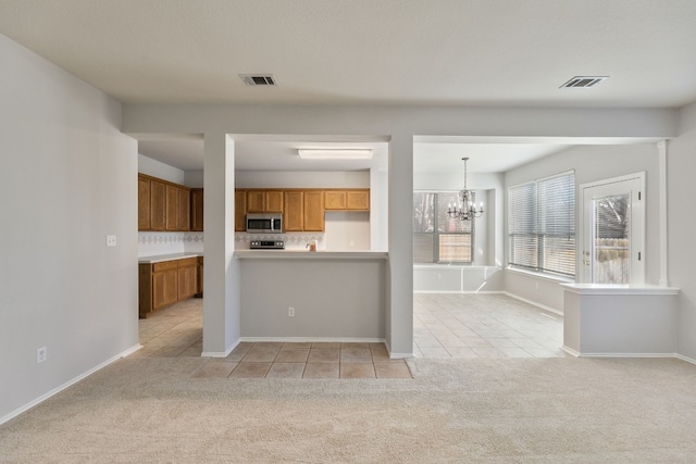 kitchen featuring backsplash, a chandelier, hanging light fixtures, and light colored carpet