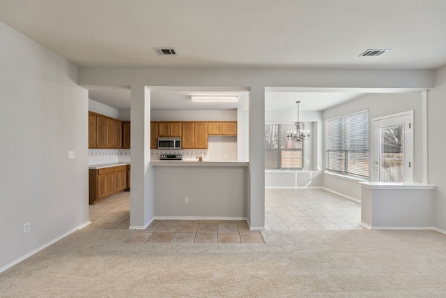 30004 Oakland Hills Dr, Georgetown, TX 78628 - kitchen featuring stainless steel microwave, light tile patterned floors, light colored carpet, a chandelier, and light countertops