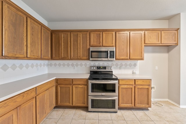 30004 Oakland Hills Dr, Georgetown, TX 78628 - kitchen featuring appliances with stainless steel finishes, light countertops, tasteful backsplash, and brown cabinets