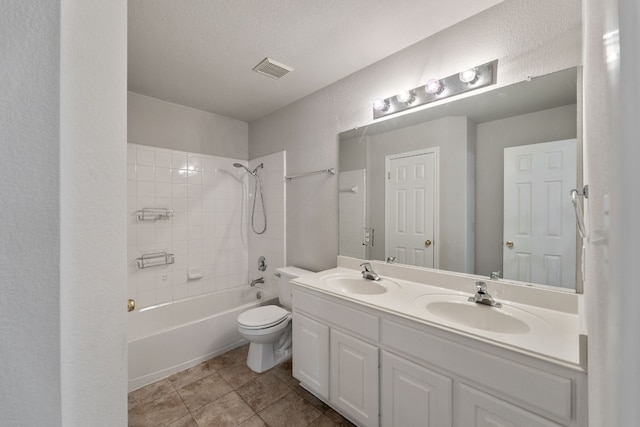 full bathroom featuring tile patterned floors, vanity, a textured ceiling, tiled shower / bath combo, and toilet