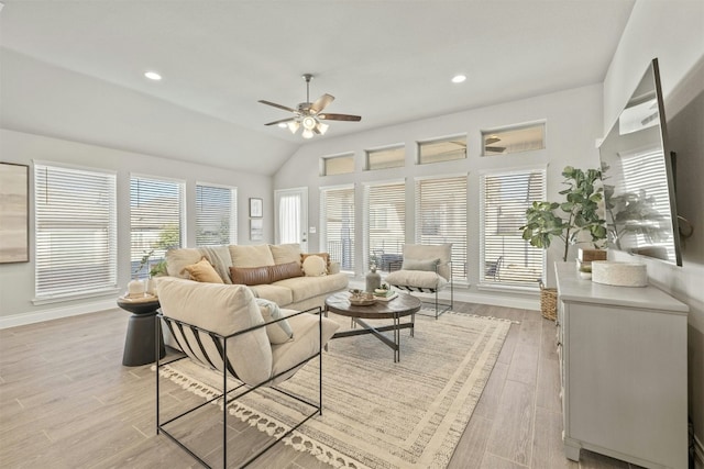 living room with ceiling fan, light hardwood / wood-style floors, and vaulted ceiling