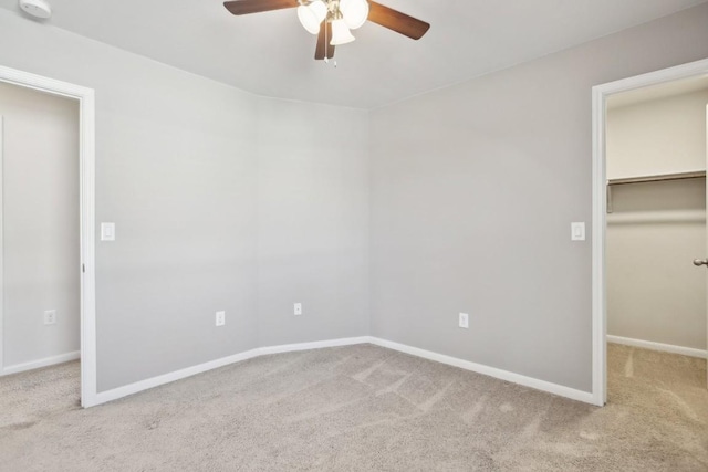 unfurnished bedroom with a spacious closet, a closet, ceiling fan, and light colored carpet