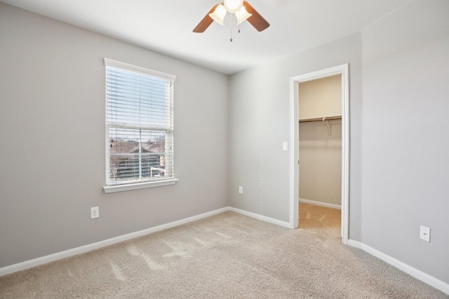 unfurnished bedroom featuring ceiling fan, light colored carpet, a walk in closet, and a closet