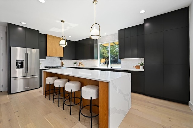 kitchen with pendant lighting, a large island, light wood-type flooring, and high end refrigerator