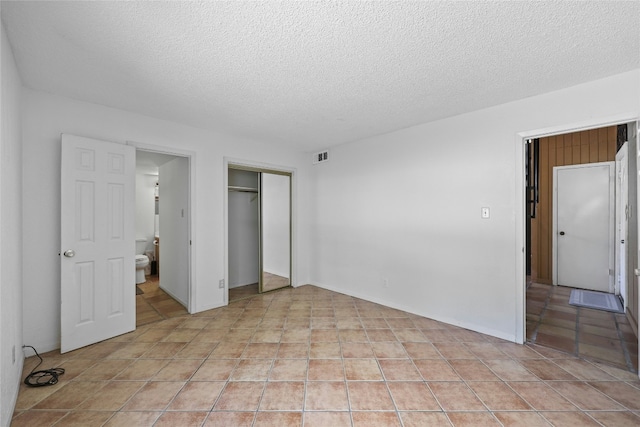 unfurnished bedroom featuring light tile patterned floors, a textured ceiling, and a closet