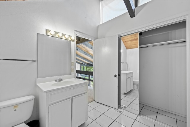 bathroom with tile patterned floors, vanity, toilet, and vaulted ceiling