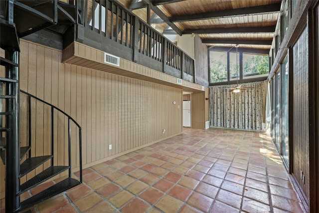 interior space featuring ceiling fan, wooden ceiling, beamed ceiling, a towering ceiling, and wooden walls