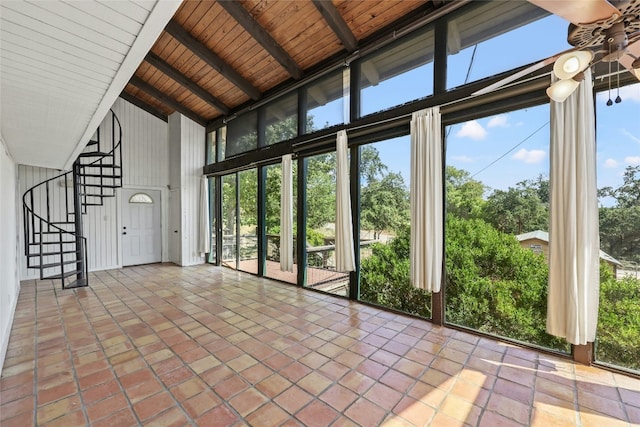 unfurnished sunroom with lofted ceiling with beams, a wealth of natural light, ceiling fan, and wood ceiling