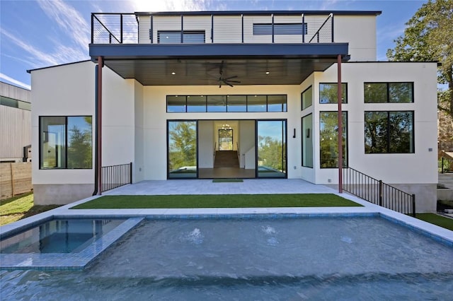 back of house with ceiling fan, a balcony, and a pool with hot tub