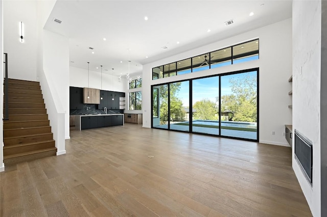 unfurnished living room featuring a high ceiling, light hardwood / wood-style floors, and sink