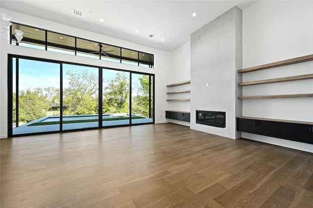 unfurnished living room featuring a high ceiling and hardwood / wood-style flooring