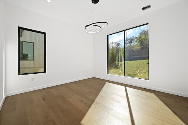 unfurnished dining area featuring a healthy amount of sunlight, dark hardwood / wood-style floors, and a notable chandelier