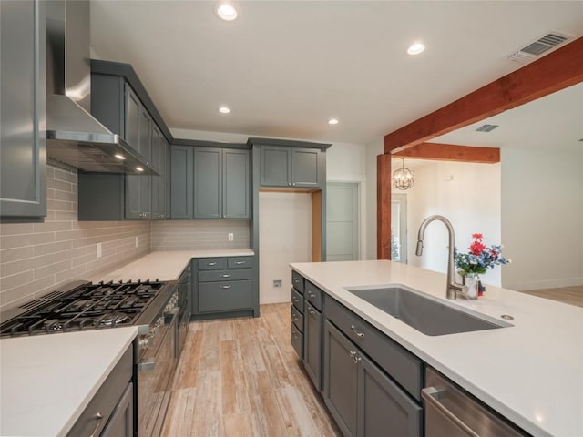 kitchen with beam ceiling, sink, stainless steel appliances, wall chimney range hood, and decorative backsplash