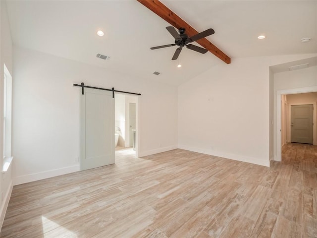 empty room with a barn door, ceiling fan, lofted ceiling with beams, and light hardwood / wood-style floors