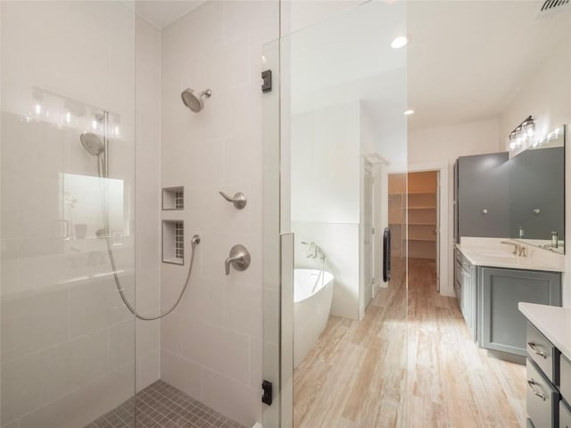 bathroom featuring plus walk in shower, vanity, and hardwood / wood-style flooring