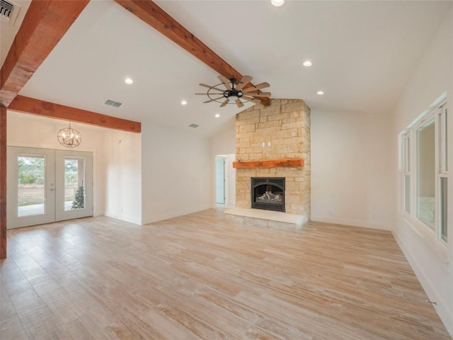 unfurnished living room featuring french doors, light wood-type flooring, ceiling fan with notable chandelier, lofted ceiling with beams, and a fireplace