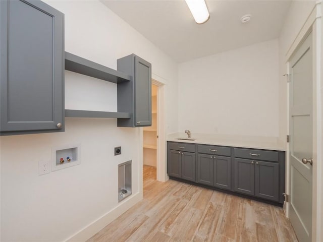 clothes washing area featuring sink, cabinets, electric dryer hookup, hookup for a washing machine, and light hardwood / wood-style floors