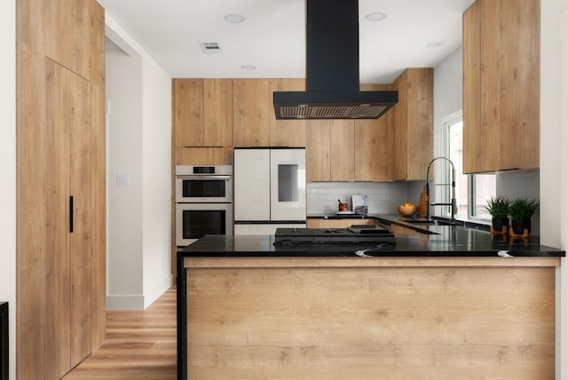 kitchen with kitchen peninsula, ventilation hood, double oven, sink, and white refrigerator