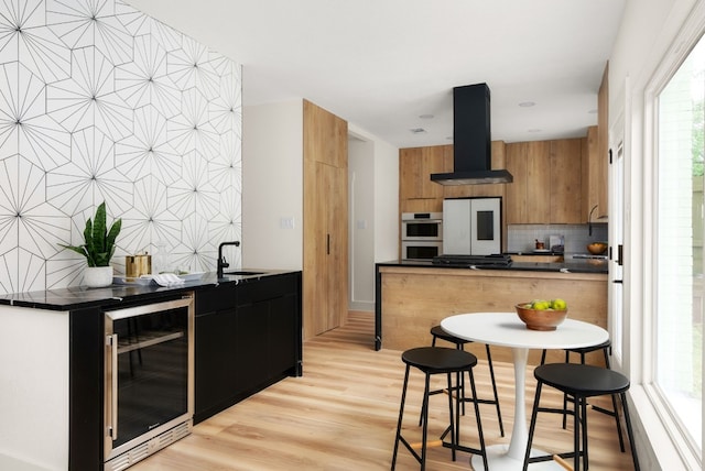 kitchen with exhaust hood, sink, light wood-type flooring, white fridge, and beverage cooler