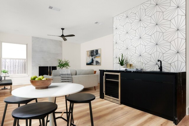 dining area featuring wine cooler, ceiling fan, and light wood-type flooring