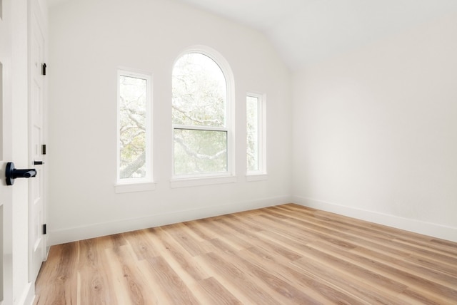 unfurnished room with light wood-type flooring and lofted ceiling