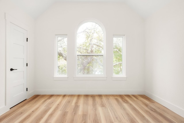 spare room featuring vaulted ceiling and light wood-type flooring