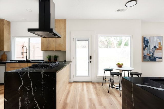 kitchen featuring backsplash, a healthy amount of sunlight, sink, and island exhaust hood