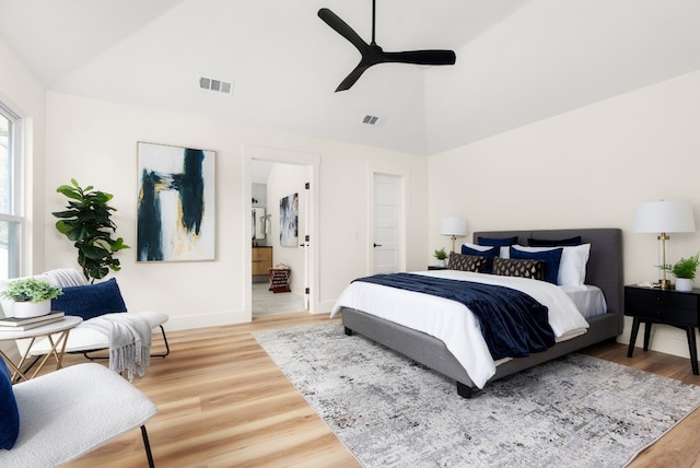 bedroom with hardwood / wood-style flooring, ceiling fan, connected bathroom, and vaulted ceiling