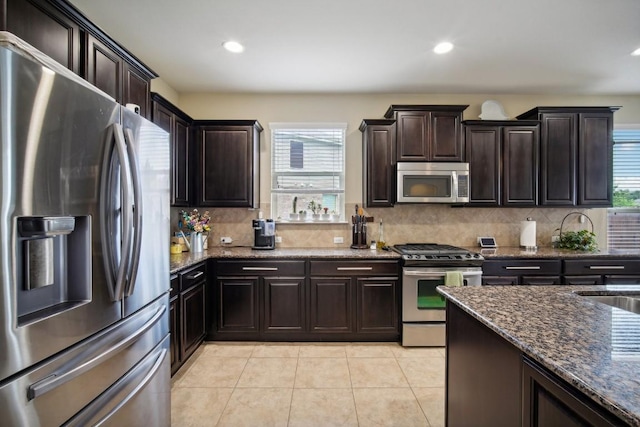 kitchen featuring appliances with stainless steel finishes, dark brown cabinets, and dark stone countertops