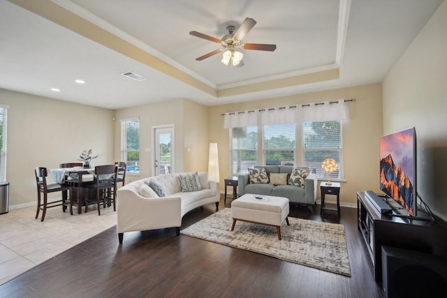 living room featuring wood-type flooring, a raised ceiling, and ceiling fan