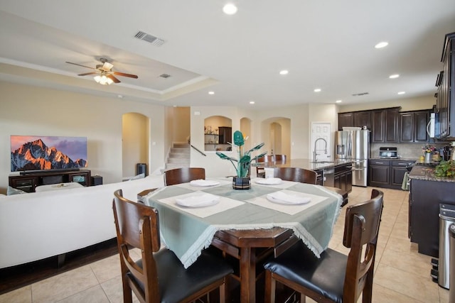 tiled dining area with a raised ceiling, ceiling fan, and crown molding