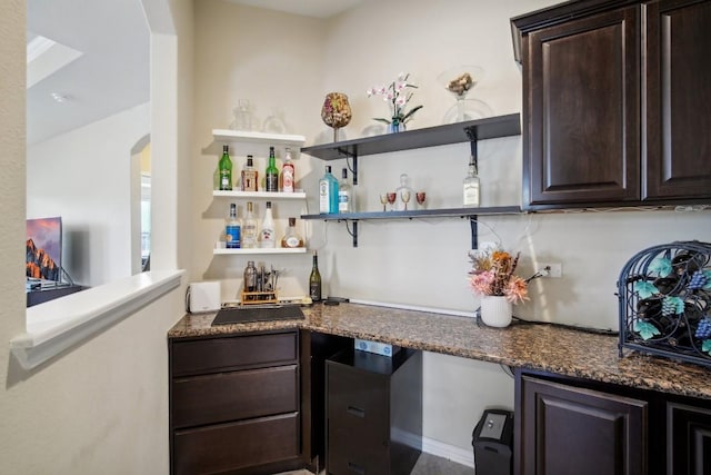 bar with dark brown cabinets and dark stone counters