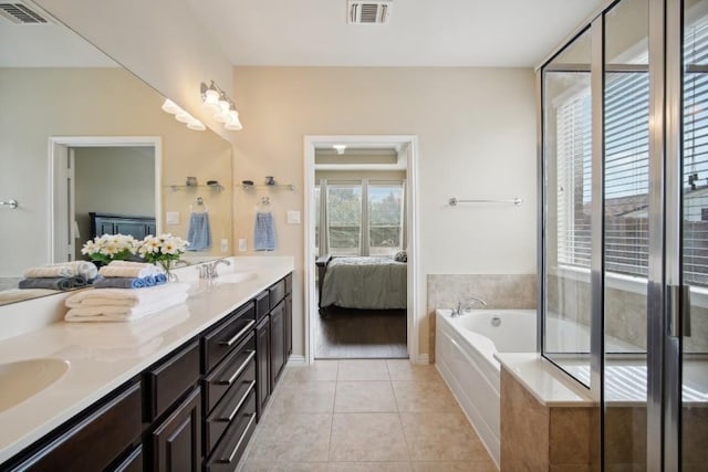 bathroom featuring tile patterned floors, vanity, and tiled bath