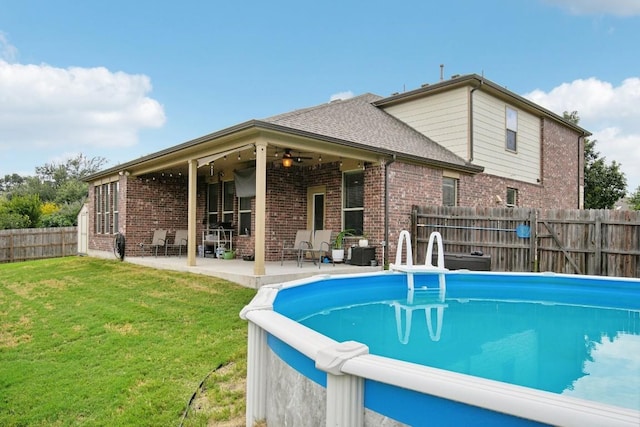 view of pool with a patio, ceiling fan, and a lawn