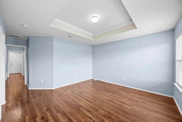 unfurnished room featuring dark hardwood / wood-style flooring, crown molding, and a tray ceiling