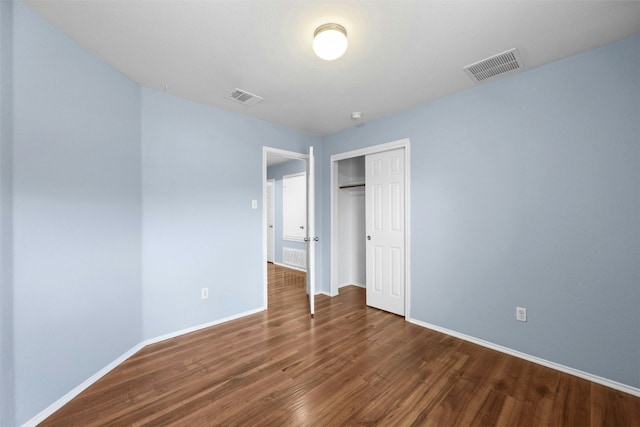 unfurnished bedroom with a closet and dark hardwood / wood-style floors