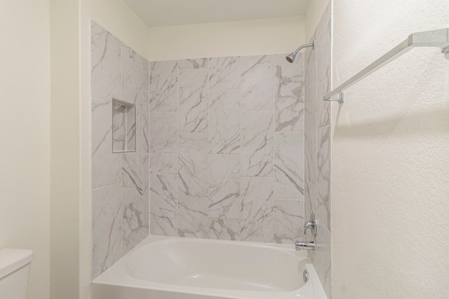 bathroom with toilet and tiled shower / bath