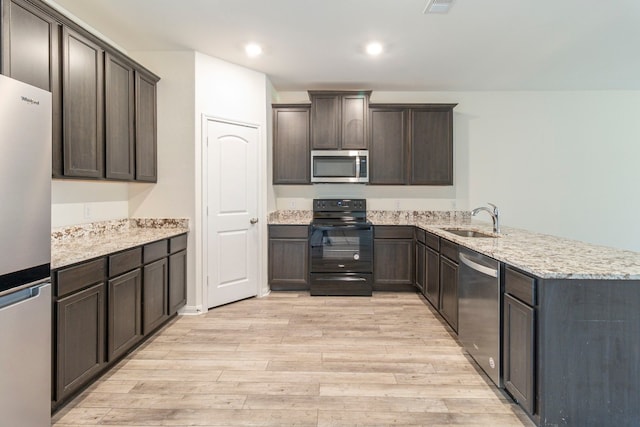 kitchen with kitchen peninsula, appliances with stainless steel finishes, dark brown cabinetry, sink, and light hardwood / wood-style floors