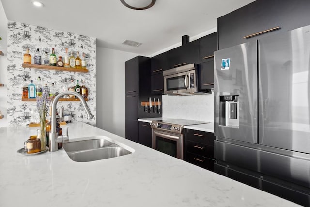 kitchen with backsplash, sink, light stone countertops, and stainless steel appliances