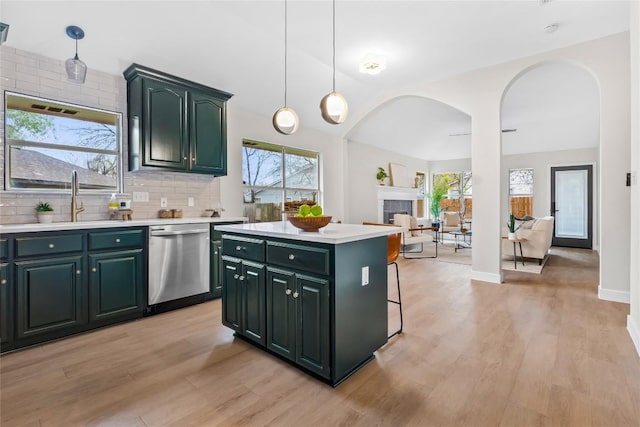 kitchen featuring dishwasher, a tile fireplace, sink, decorative backsplash, and a kitchen island