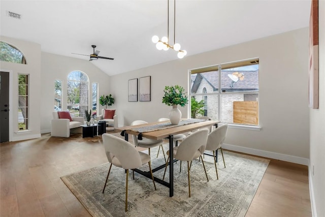 dining area with vaulted ceiling, a wealth of natural light, light hardwood / wood-style floors, and ceiling fan with notable chandelier