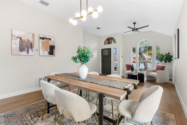 dining space featuring lofted ceiling, hardwood / wood-style floors, and ceiling fan with notable chandelier