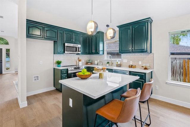 kitchen with decorative backsplash, a kitchen island, a healthy amount of sunlight, and appliances with stainless steel finishes