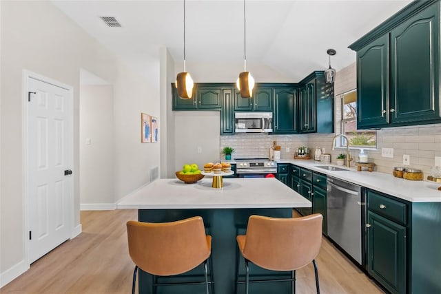 kitchen featuring sink, hanging light fixtures, decorative backsplash, a kitchen island, and stainless steel appliances