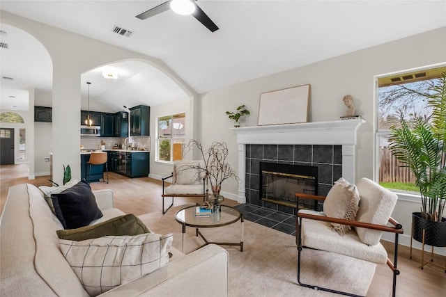 living room with hardwood / wood-style flooring, ceiling fan, a fireplace, and vaulted ceiling