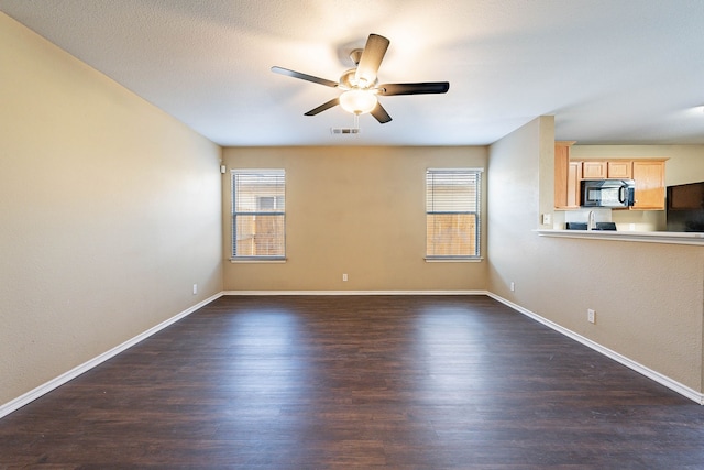 unfurnished living room with ceiling fan, a healthy amount of sunlight, and dark hardwood / wood-style floors